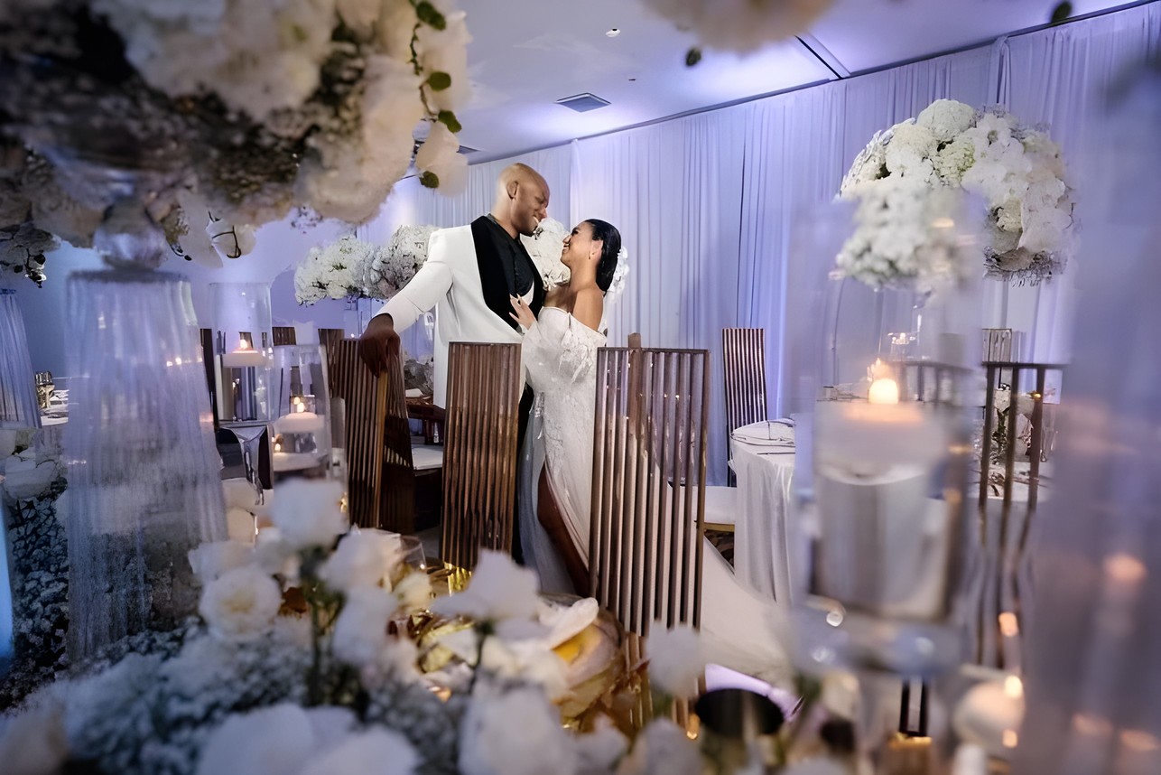 Bride and groom laughing in front of a white floral wedding backdrop by Sharp Designs