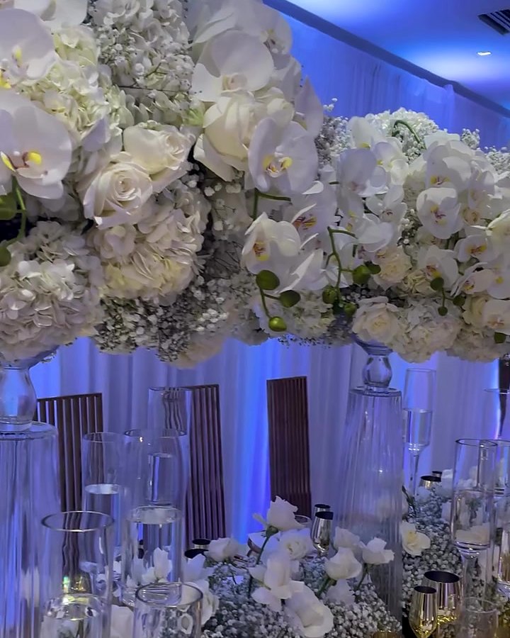 Tall white orchid and rose wedding centerpiece over gold glassware and candlelight by Sharp Designs